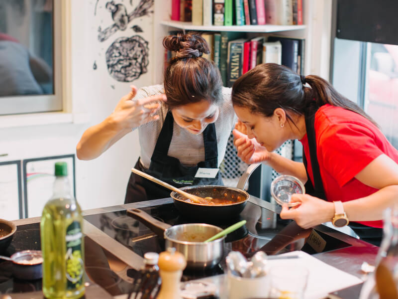 Two women smelling food at a cooking class